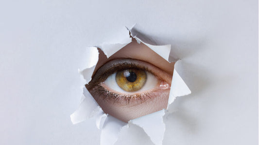 Oeil vert d'une femme qui regarde dans à travers un trou
